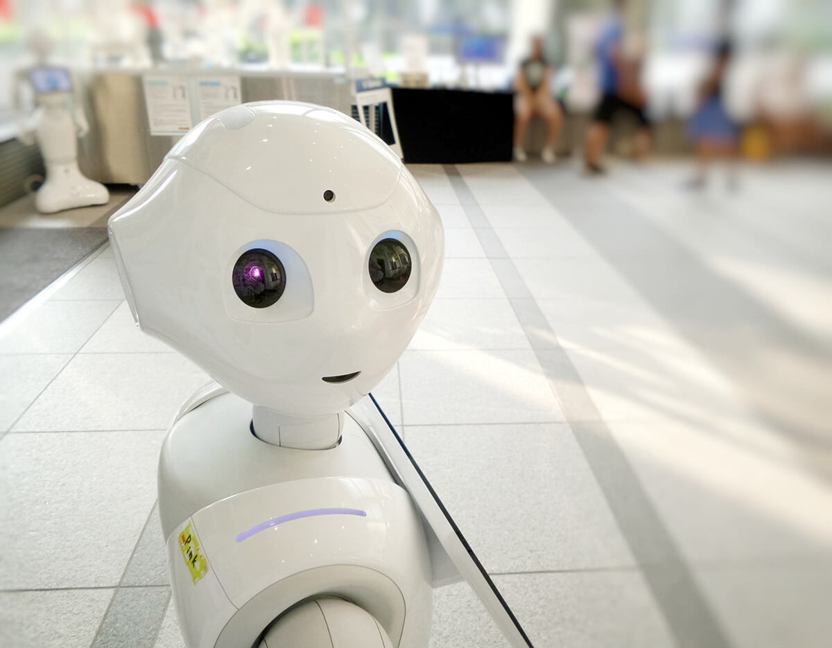 Robot looking into camera, people in blurry background 
